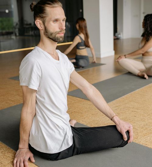 A diverse group of people sitting comfortably on yoga mats before a class.